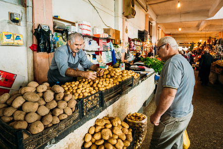 Batumi, Georgia - May 28, 2016: Side View Of Two Mature Georgian Men, The Buyer And Dealer Selling The Potato Of A New Crop At The Market Bazaar.のeditorial素材