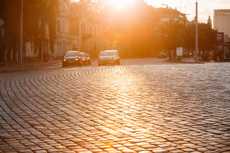 Vilnius, Lithuania  - July 8, 2016: Traffic On Zygimantu Street In Old Town. Moving Cars With Luminous Headlights On The Paved Road In Yellow Sunlight Of Sunset Sunrise.のeditorial素材