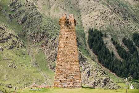 Ancient Old Stone Watchtower On Mountain Background In Sioni Village, Kazbegi District, Mtskheta-Mtianeti Region, Georgia. Spring Or Summer Season. Famous Landmarks And Places In Kazbegi District.の写真素材