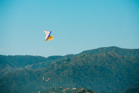 Motorized Hang Glider Flying Over Mountain Hills On Blue Clear Sunny Sky Background.
