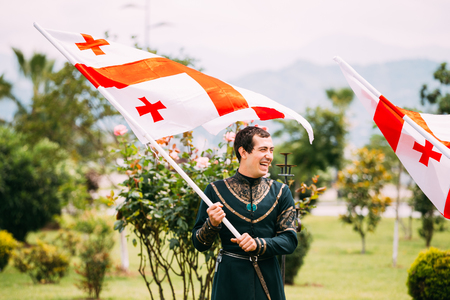 Batumi, Adjara, Georgia - May 26, 2016: Young man in Georgian national dress holding a national flag in celebration of the national holiday - the Independence Day of Georgia.のeditorial素材