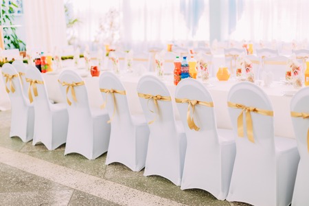 Decorative White Mantles And Colored Ribbons On Chairs At Festive Table. Chairs And Table Covered With Cloth.の写真素材