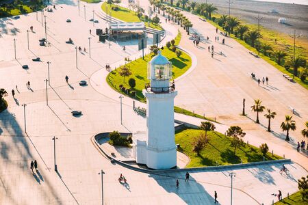 Batumi, Adjara, Georgia. Top View Of Old Pitsunda Lighthouse In Miracle Park. People Walk Along Promenade, Illuminated By Setting Sun In Golden Hour At Sunset.の写真素材