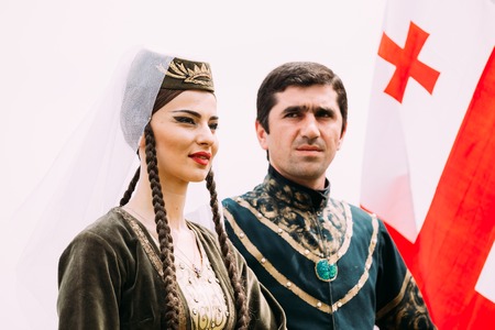 Batumi, Adjara, Georgia - May 26, 2016: Young couple of man and woman in Georgian national clothes on flag background in celebration of the national holiday - the Independence Day of Georgia.のeditorial素材
