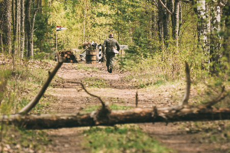 Unidentified Re-enactor Dressed As German Wehrmacht Infantry Soldier In World War II Running Toward A Checkpoint Along A Forest Road. Spring Seasonの写真素材