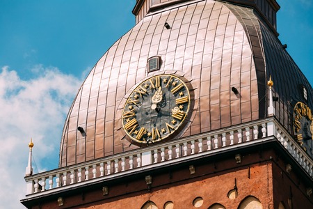 Close Up Of Clock On Tower Of Riga Dome Cathedral In Riga, Latvia. Sunny Sunset Blue Sky Background.の写真素材