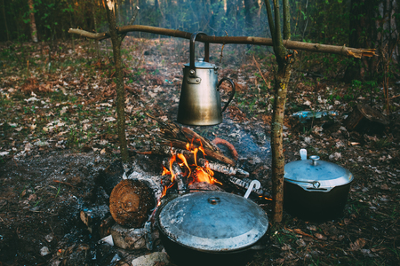 Old Retro Iron Camp Kettle And Pans Boils Water On A Fire In Forestの写真素材
