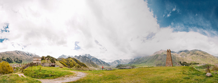 Panorama Of Ancient Church And Old Stone Watchtower On Mountain Background In Sioni Village, Kazbegi District, Mtskheta-Mtianeti Region, Georgia. Spring Or Summer Season. Famous Landmarks And Places In Kazbegi District.の写真素材