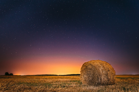 Night Starry Sky Above Field Meadow With Hay Bale After Harvest.の写真素材