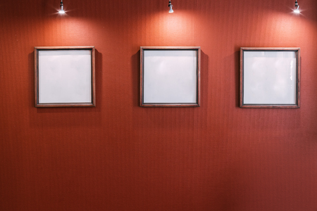 Three White Empty Frames On Red Wallの写真素材