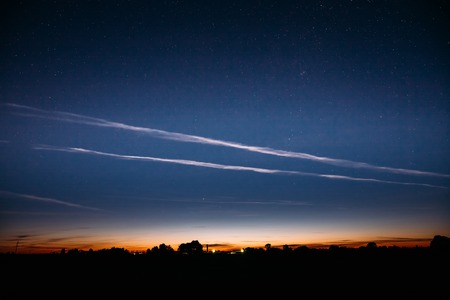 Blue Night Starry Sky And Noctilucent Clouds Above Summer Countryside Landscape. Glowing Stars And Night Shining Clouds. Tenuous Cloud-like Phenomena In The Upper Atmosphere Of Earth.の写真素材
