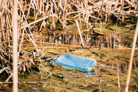 Old Plastic Canister Floats In Water Of Swamp Or Pond. Used Empty Packing Materials Left In Water....