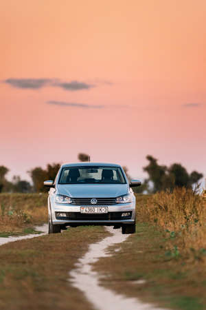 Gomel, Belarus - September 14, 2016: Volkswagen Polo Vento Car Sedan Parking Near Country Road In Autumn Field. Sunset Sunrise Sky On A Background In Sunny Evening.のeditorial素材