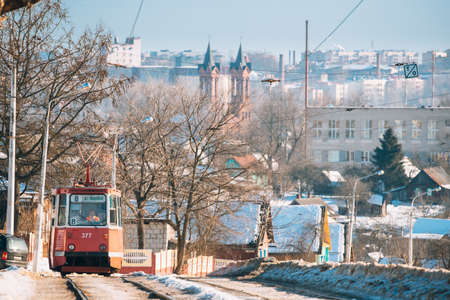 Vitebsk, Belarus - February 16, 2017: Public Old Retro Tram Of Route Number Eight With Female Woman Driver Moving Near Private Sector And Old Cathedral Of St. Barbara In Winter Day.のeditorial素材