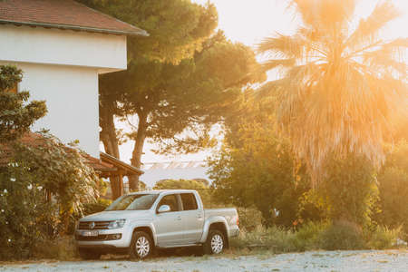 Gray Volkswagen Amarok pickup truck parked in countryside during summer sunset.のeditorial素材