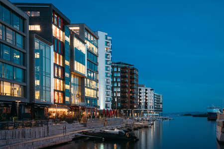 Oslo, Norway. Night View Embankment And Residential Multi-storey Houses In Aker Brygge District. Summer Evening. Residential Area Reflected In Sea Waters. Famous And Popular Placeのeditorial素材