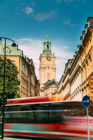 Stockholm, Sweden. Red Bus In Motion Blur Rides Near Old Town With Tower Of Storkyrkan - The Great Church Or Church Of St. Nicholas. Stockholm Cathedral Is The Oldest Church In Gamla Stan.の写真素材