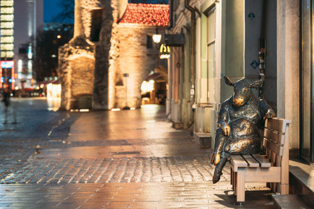 Tallinn, Estonia - December 5, 2016: Black Angus Sculpture - Bronze Bull Cow Statue That Sitting On Bench Near Cafe. Night View.のeditorial素材