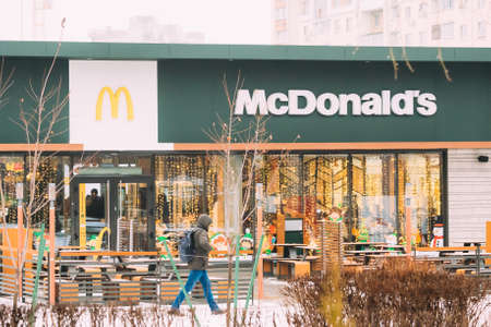 Gomel, Belarus - January 9, 2020: Man walking near modern building of McDonalds restaurant. McDonald's Corporation is the world's largest chain of hamburger fast food restaurantsのeditorial素材