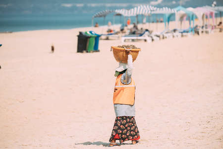 Arossim, Goa, India - February 18, 2020: Woman Pick Up Trash On Beach In Sunny Day. Woman Carrying Garbage Basket On Her Headのeditorial素材