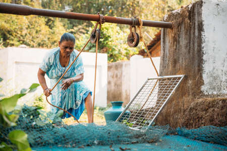Velha Goa, Goa, India - February 18, 2020: Woman Draws Water From Well.のeditorial素材