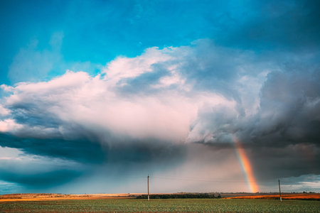 Dramatic Sky During Rain With Rainbow On Horizon Above Rural Landscape Field. Agricultural And...