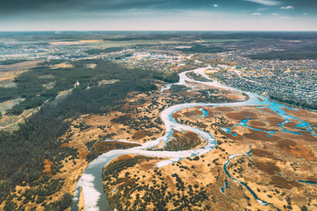 Belarus, Europe. Aerial View Curved River And Small Town In Early Spring Landscape. River bends Curves and dry grass landscape. Top View Of Beautiful European Nature From High Attitude. Drone View. Birds Eye Viewの写真素材