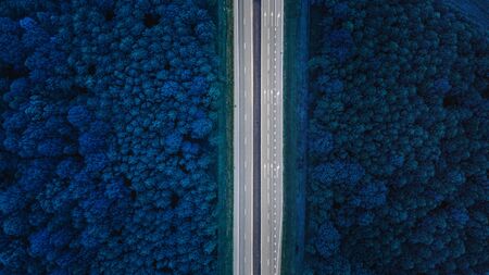 Aerial View Of Highway Road Through Blue Forest Landscaper.Toned Photo. Top View Flat View Of Highway Motorway Freeway From High Attitude. Trip And Travel Conceptの写真素材
