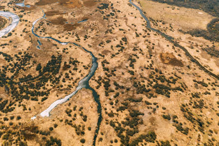 Aerial View Curved River In Early Spring Landscape. River bends Curves and dry grass landscape. Top View Of Beautiful European Nature From High Attitude. Drone View. Birds Eye Viewの写真素材
