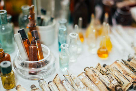 Many Old Medical Glass Capacity. Detail Of Retro Chemical Pharmaceutical Science Researches. Many Small Vintage Bottles And Glassware Different Sizes And Colorsの写真素材