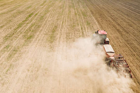 Aerial View. Tractor With Seed Drill Machine Sowing The Seeds For Crops In Spring Season. Beginning Of Agricultural Spring Season. Countryside Rural Field Landscapeの写真素材