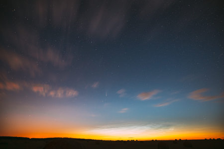 Night Starry Sky With Glowing Stars Above Countryside Landscape. Light Cloudiness Overcast Above...