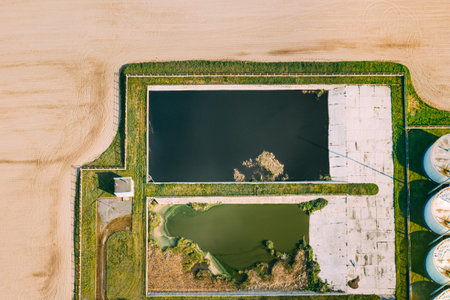 Aerial View Of Retention Basins, Wet Pond, Wet Detention Basin Or Stormwater Management Pond Near Biogas Bio-gas Plant From Pig Farm. Artificial Pond With Vegetation Around Perimeter.の写真素材
