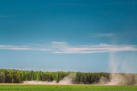 Tractor With Seed Drill Machine Sowing The Seeds For Crops In Spring Season. Beginning Of Agricultural Spring Season. Countryside Rural Field Landscapeの写真素材