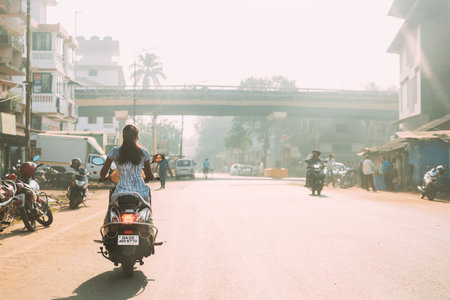 Margao, Goa, India. Woman Driver Riding On Scooters Motorcycle On Street In Sunny Light.のeditorial素材