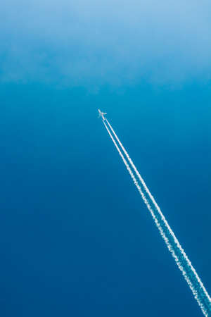 Airplane In Sky With Plane Trailsの写真素材
