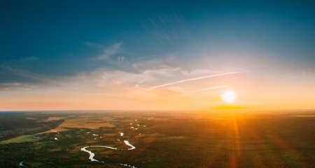 Belarus. Aerial View. Beautiful Sunset Sun Sunshine Above Summer Green Forest And River Landscape In Sunny Evening. Top View Of European Nature From High Attitude In Summer Sunrise. Birds Eye Viewの写真素材