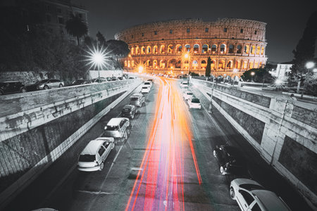 Rome, Italy. Colosseum Also Known As Flavian Amphitheatre In Evening Or Night Time. Night Traffic Light Trails Near Famous World Landmark. All colors except red, pink and yellow are reducedの写真素材
