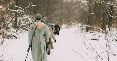 Men Dressed As White Guard Soldiers Of Imperial Russian Army In Russian Civil War Times Marching Through Snowy Winter Forest. Historical Reenactment 1917-1922.の写真素材