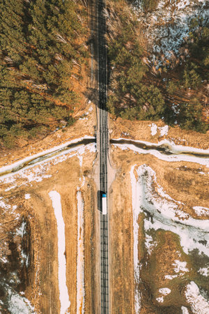 Aerial View Of Highway Road Through Spring Forest Landscape. Top View Of White Truck Tractor Unit Prime Mover Traction Unit In Motion On Freeway. Business Transportation, Trucking Industry. Flat Viewの写真素材