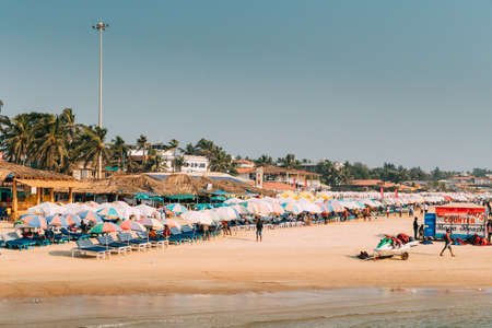 Mapusa, Anjuna, Goa, India. People Visit And Relax On Baga Beach At Sunny Evening Under Blue Sky.のeditorial素材