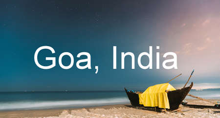Goa, India. Real Night Sky Stars. Natural Starry Sky Blue Color Above Sea Seascape Ocean Beach. Background. Parked Old Wooden Boat At Coastの写真素材