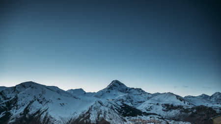Stepantsminda, Georgia. Winter Night Starry Sky With Glowing Stars And Peak Of Mount Kazbek Covered With Snow. Beautiful Night Georgian Winter Landscapeの写真素材