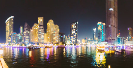 Night Skyline Abstract Boke Bokeh Background. Design Backdrop. Beautiful Night view of high-rise buildings of residential district in Dubai Marina And Tourist Boat, Sightseeing Boat Sailing On Dubai Marina. Panorama, Panoramic View.の写真素材