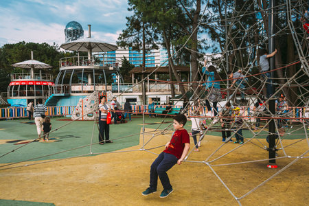 Batumi, Adjara, Georgia. Children and adults play on playground on city street near waterfront.のeditorial素材