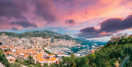 Monaco, Monte Carlo cityscape. Real estate architecture on mountain hill background. Many high-rise buildings in downtown area. Yachts moored at town quay In Sunny Summer Day. Altered Sunset Skyの写真素材
