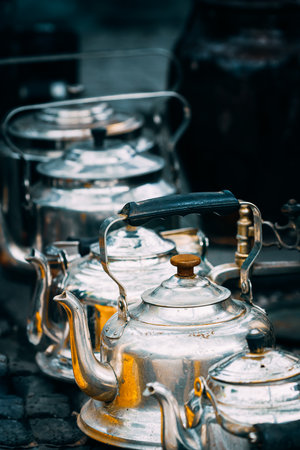 Close Up View On Metal Vintage Tea Pots In A Row At Flea Market. Second Life For Old Things. Old Tableware For Coffee And Tea. Tea Party Concept And Hospitalityの写真素材
