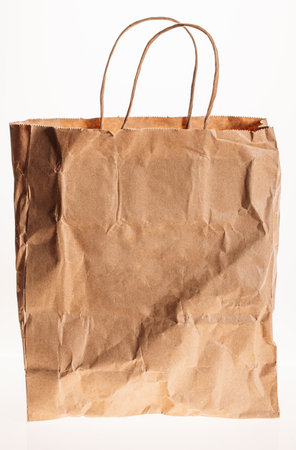 Crumpled Brown Shopping Paper Bag Isolated On White Background. Used Craft Paper Shopping Bag. Recycled Paper Grocery Bag. Concept Of Shopping And Recyclingの写真素材