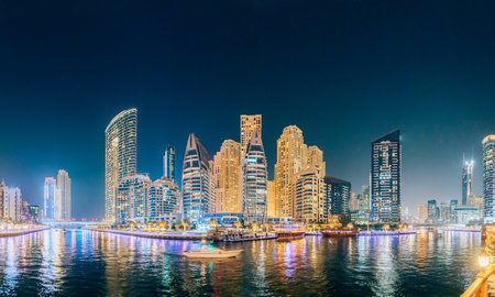 Beautiful Night view of high-rise buildings of residential district in Dubai Marina And Tourist Boat, Sightseeing Boat Sailing On Dubai Marina. Panorama, Panoramic Viewの写真素材