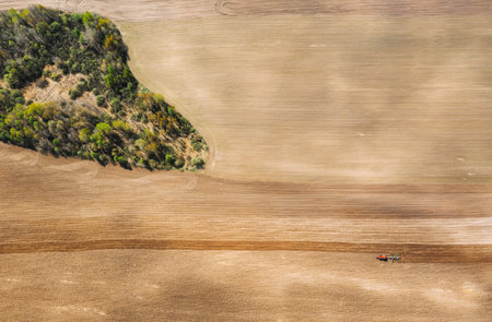 Tractor Plowing Field In Spring. Beginning Of Agricultural Season. Cultivator Pulled By A Tractor In Countryside Rural Field. Countryside Field Landscape. Aerial View. Top Flat Viewの写真素材